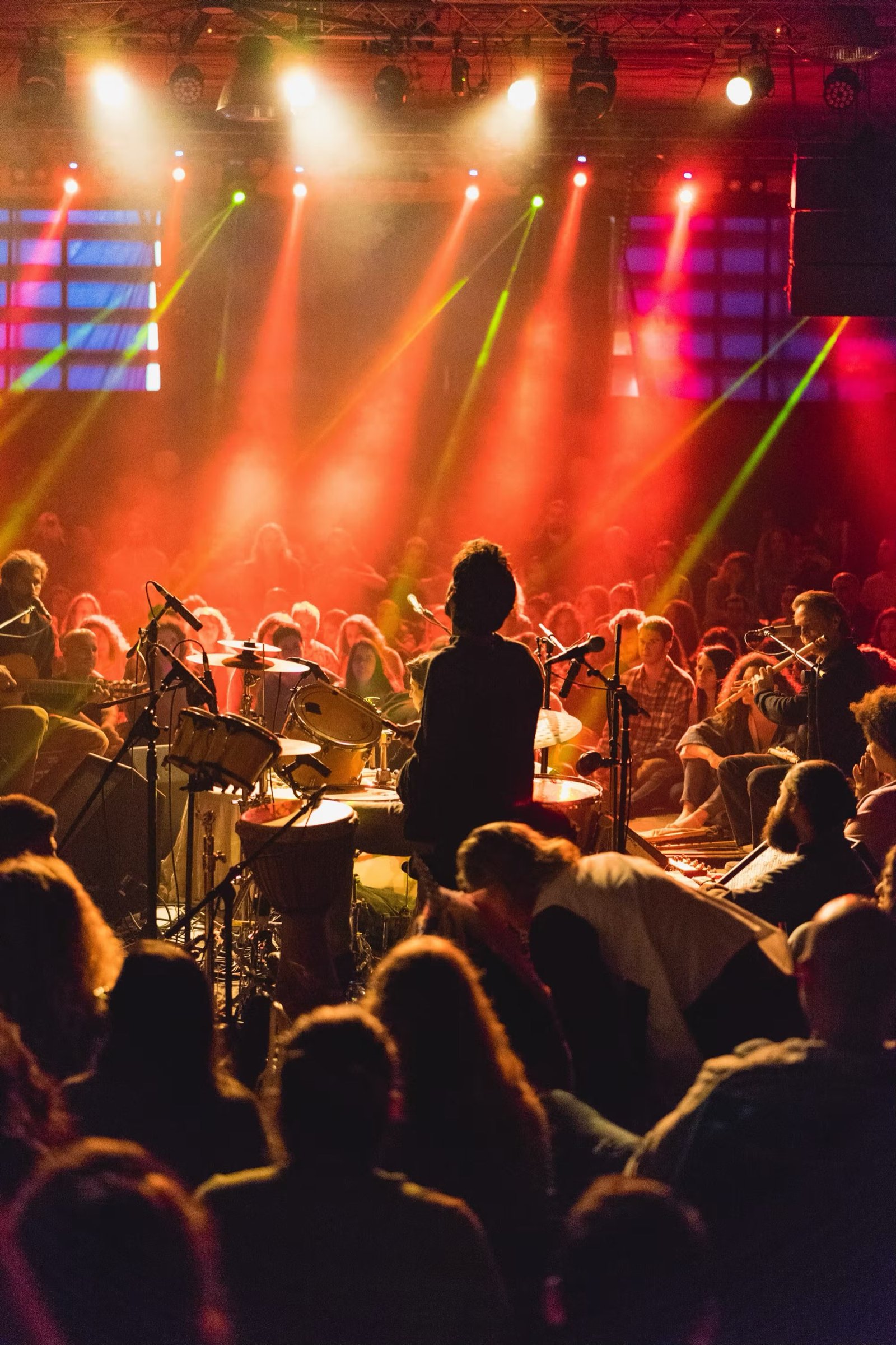 A band mid-set under colorful stage light, crowd close in.
