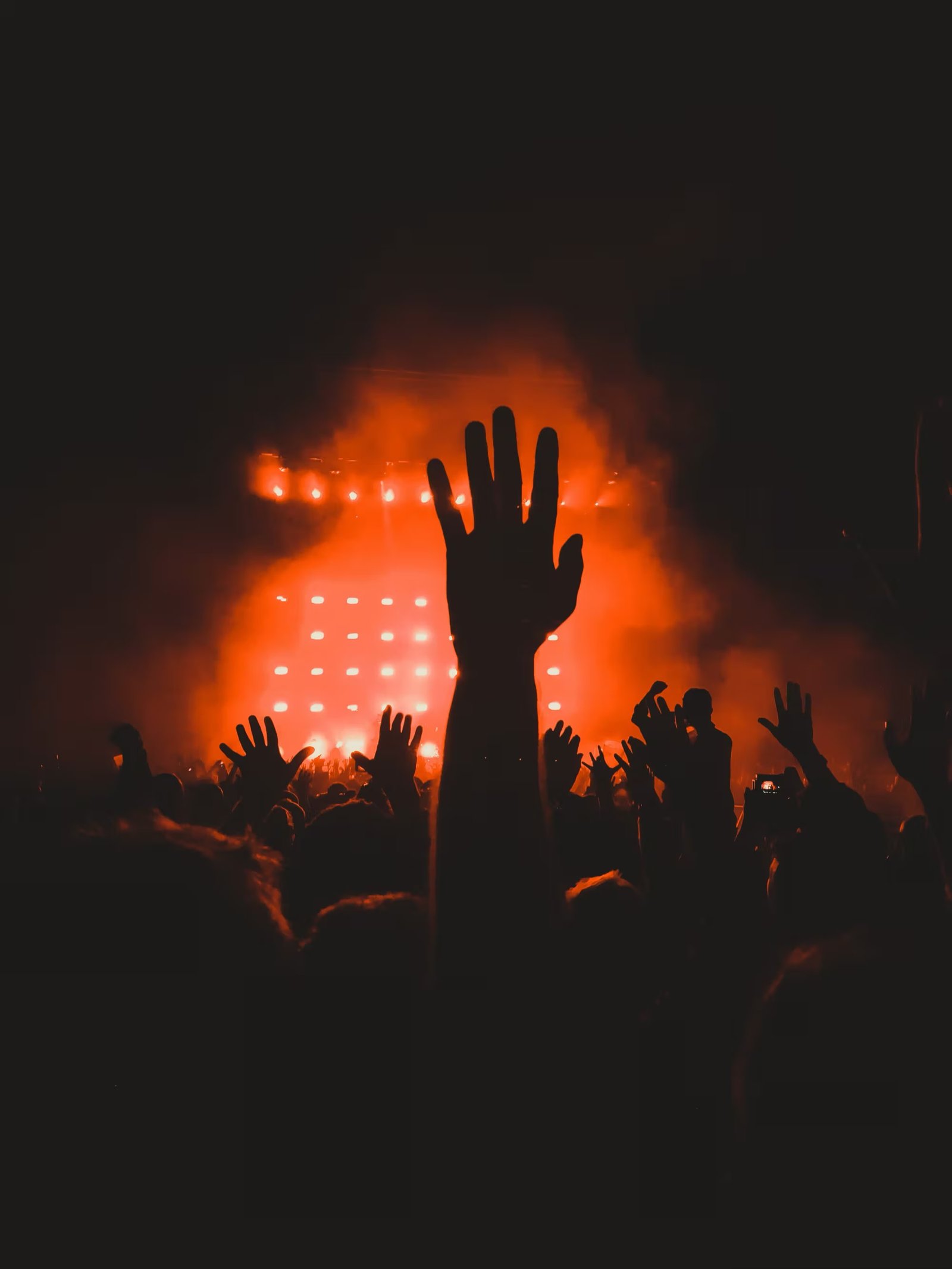 A single hand raised against a wall of red stage light.